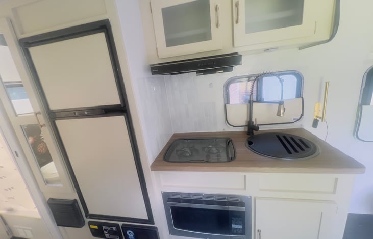 Two burner propane stove, convection microwave oven, larger-than-some-campers refrigerator with separate freezer (ice cube maker included), pantry next to the fridge with necessities.