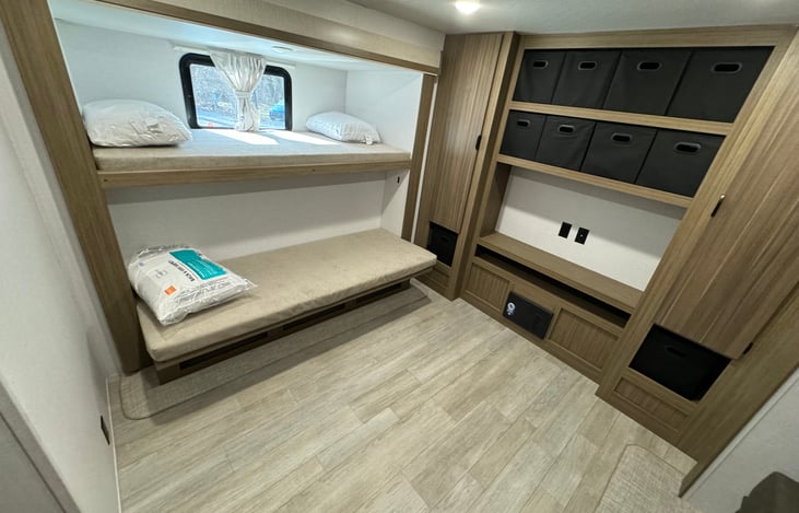 On opposing side, two more bunks, with the lower one capable of tilting up too.