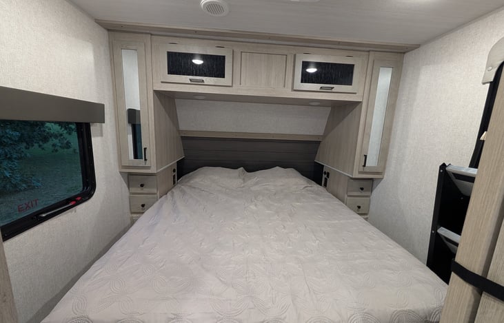 The master bedroom provides a king size bed with storage and USB chargers all around. Lift the bed and more storage is revealed. A second entry door is also seen on the far right.