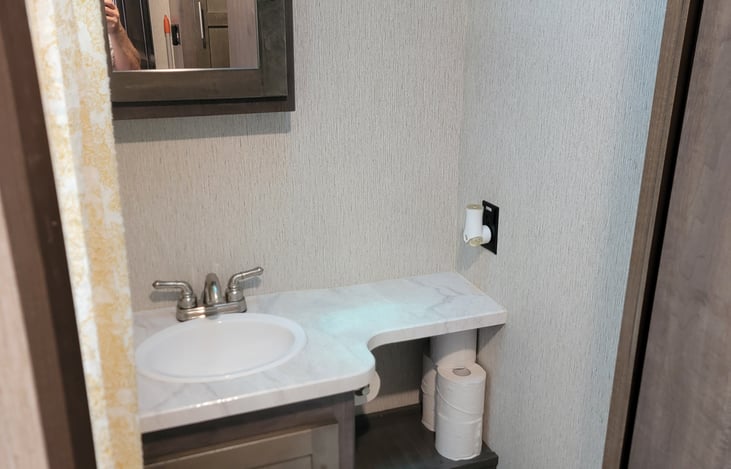 Bathroom toilet, sink, and storage.