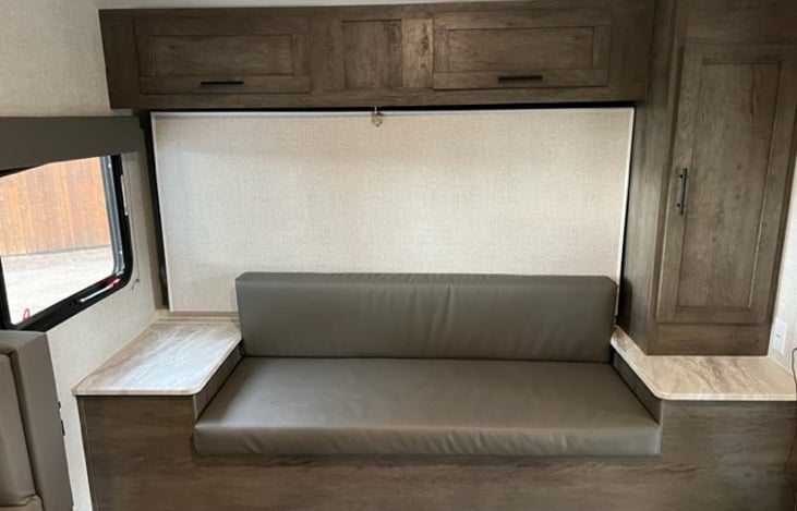 Sofa seating, overhead storage, and cabinet with hanging rod and hangers. This area converts into full size bed.