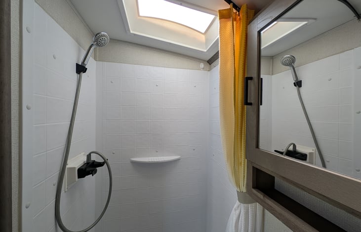 Clean bathroom with extra storage and shower.