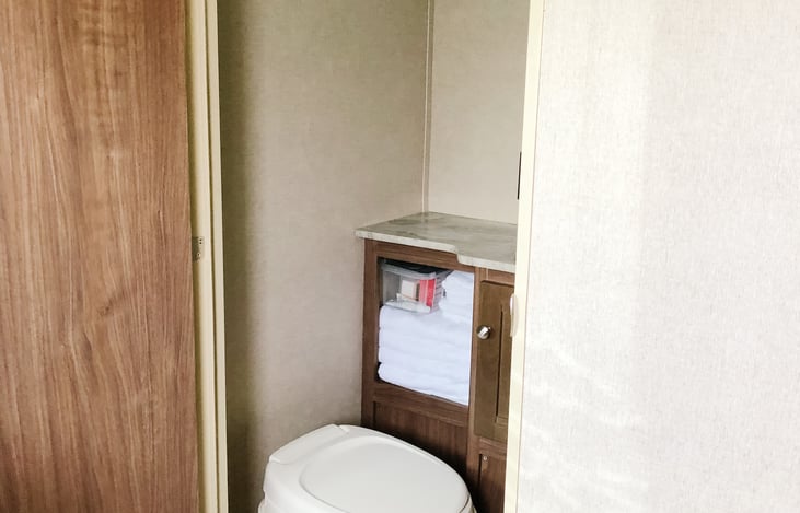 Bathroom across from front door with tub, shower, sink, toilet and toiletries (shampoo, conditioner, body wash)