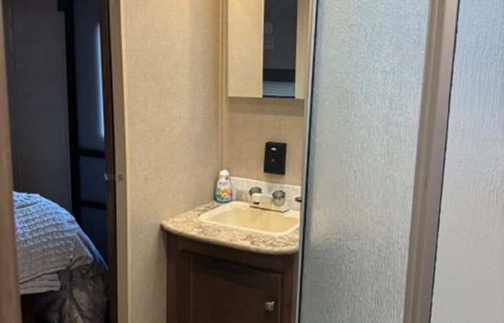 Bathroom with Medicine cabinet behind mirror, stocked with clean towels, wash clothes and hand towels, and hand soap