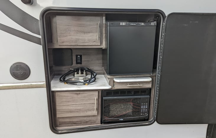 outdoor kitchenette with sink, microwave, and fridge. Plus some power outlets.