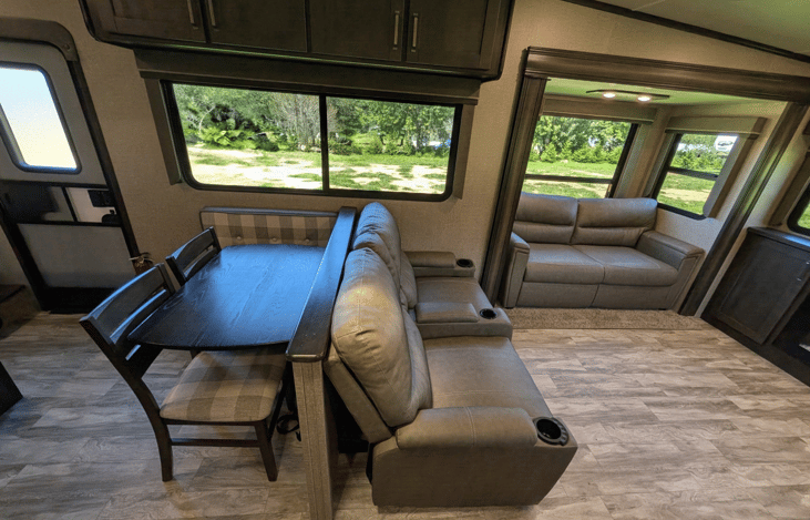 Gourmet galley & rear den retreat! Includes a 12 cu ft fridge, pantry, stove/oven, dual sofas, theater seats, 50" TV, electric fireplace, and 3 slides for spacious high-end living.