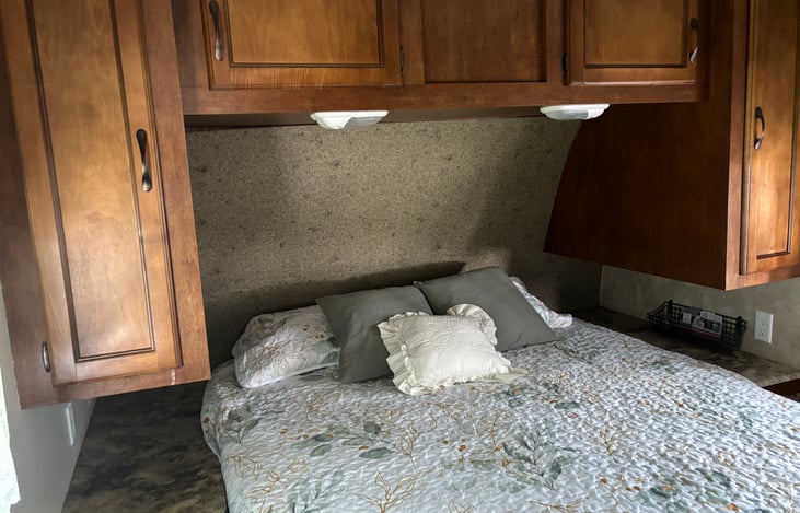 Queen bed w/all bedding.  Other bedding stored under bed which lifts up.  Hanging bars in cabinets w/room for storage basket or items, good storage above bed.