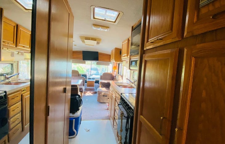 This photo shows the bathroom door, the closet just outside the bedroom and the Stove and kitchen sink. We always keep 2 rolling coolers below the fridge which can be stored below the RV if needed.