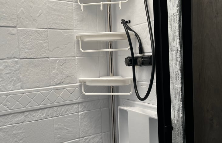 Spacious shower with 3 shelves, hooks, handheld shower head and skylight.