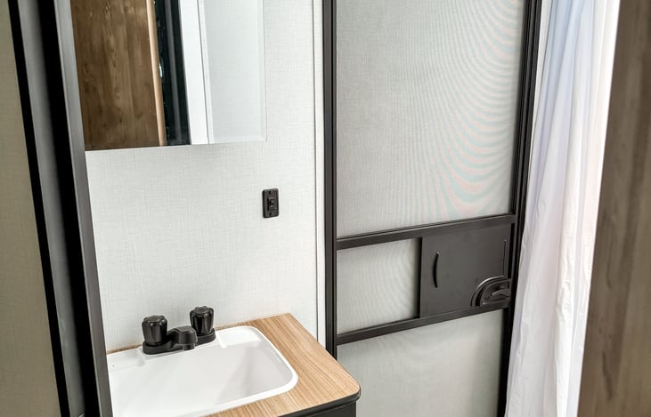 Bathroom sink and medicine cabinet. Exterior door leading to outside the RV