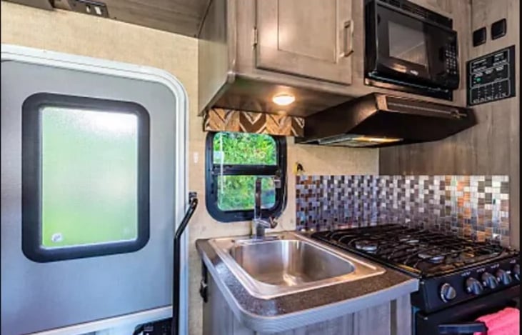 The kitchen has a sink, microwave, refigerator/freezer, and propane stove/oven
