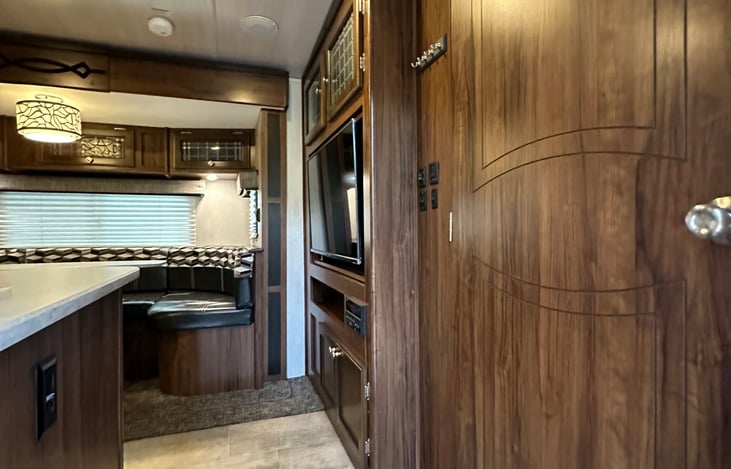 Main space includes rotating TV, convertible dinette, kitchen, and bunkbeds