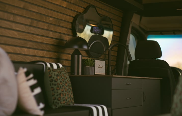 A comfortable and stylish outdoor lounge featuring a rechargeable lamp and Marshall bluetooth speakers, creating an immersive outdoor safari vibe.