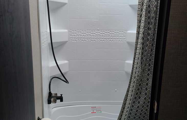 The RV features a full bathroom with a toilet and shower, giving you the convenience of home while on the road. The sink is located separately, making it easy for multiple guests to get ready.