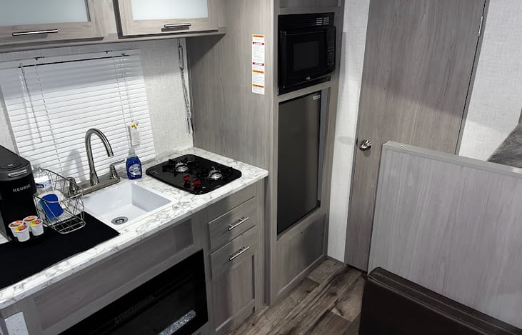 kitchen includes fridge, microwave, two burner gas stove, sink, and under sink fireplace.