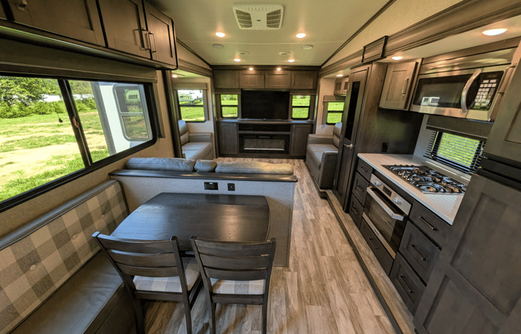 Gourmet galley & rear den retreat! Includes a 12 cu ft fridge, pantry, stove/oven, dual sofas, theater seats, 50" TV, electric fireplace, and 3 slides for spacious high-end living.
