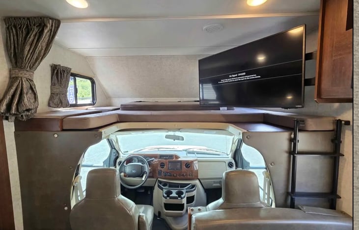 Spacious over-cab bunk sleeping area with TV. The TV can be enjoyed by the guest in the bunk or swiveled out for everyone in the RV to watch together. Bluetooth connectivity included for added enterta