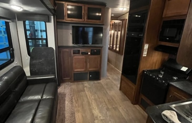 Open Floor plan with LARGE fridge, TV, Stove, Range, Microwave, Large Farm Sink, and a couch that folds into a bed. There is also a folding table that be set up in this area or the rear!