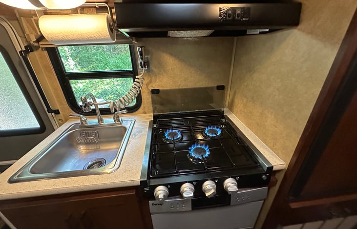 Kitchen sink with paper towel holder and extension spray faucet for easy cleaning. Propane gas stove