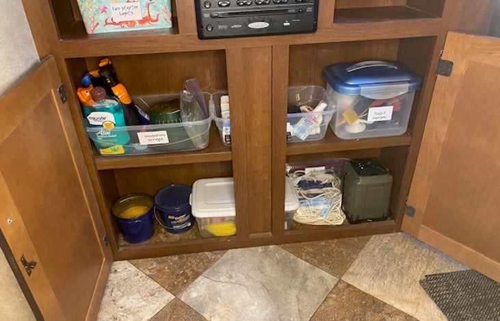 Under TV console, bug sprays, bug candles, sunscreen, simple tools kit, lantern, first aid kit, clothes line, matches, and mini flashlight