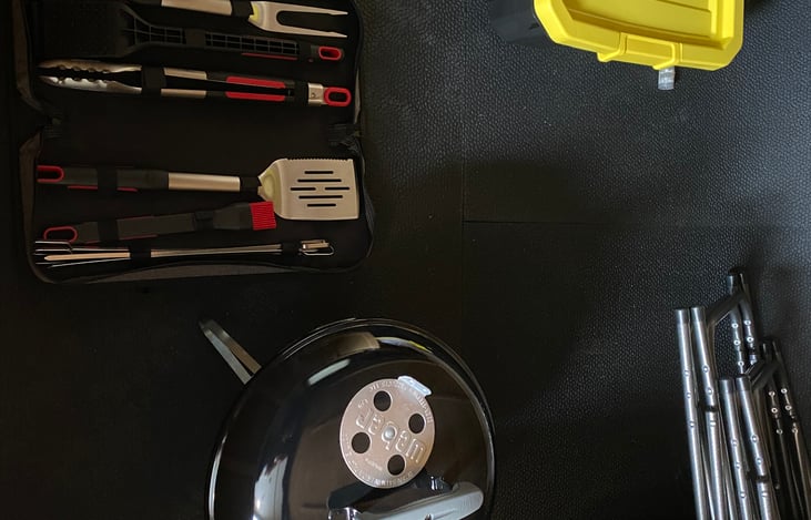 Inside storage compartment holds the provided BBQ grill, grille utensils, charcoal, lighting fluid, 2 camping chairs, utility cords, and utility hoses