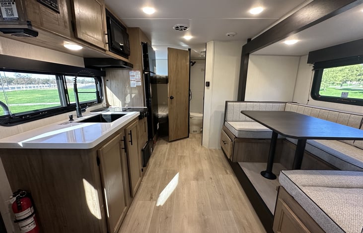 Wide interior view with kitchen, dinette, walkway, and bathroom access.