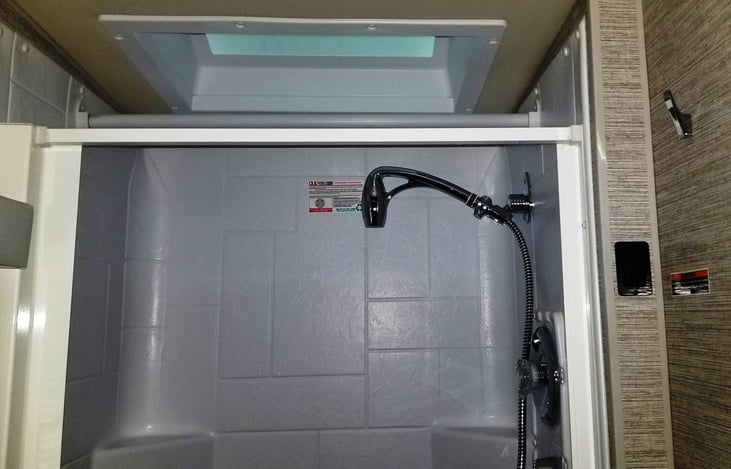 Large shower with sky light and extra clothes or towel  bar