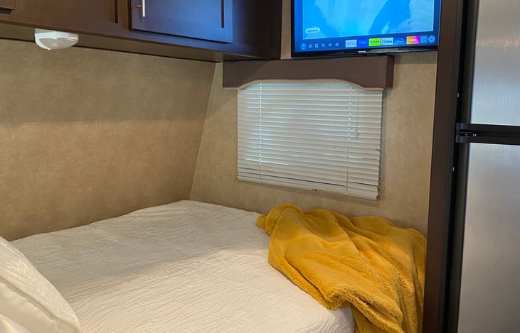 Wall mounted smart TV can be seen from bed and dining area.