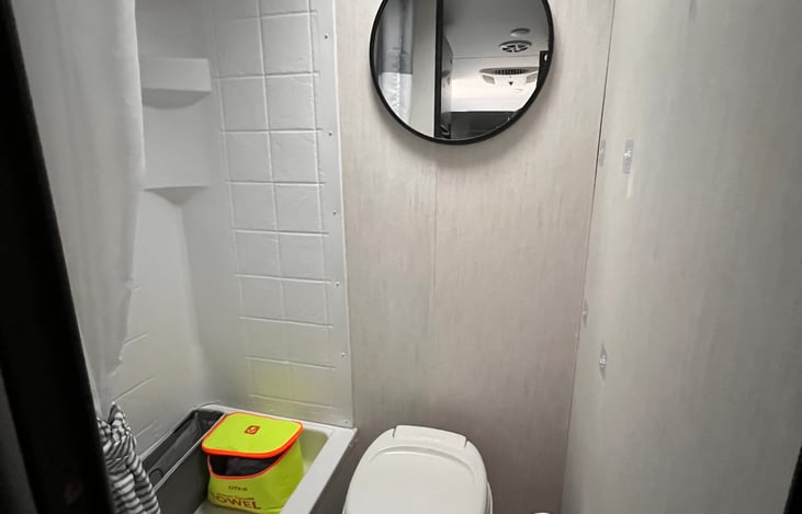 Bathroom with shower, sink, towels, hooks on the wall to hang items and baskets for storage.