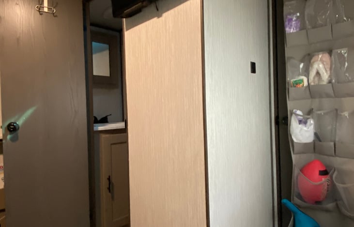 A view from inside the back bunk room looking at a little more storage area with a view of the half bath available to whoever stays in this room.