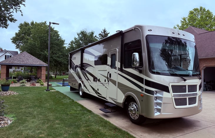 Front passenger side with dual power awning, outdoor entertainment center and outdoor kitchen.