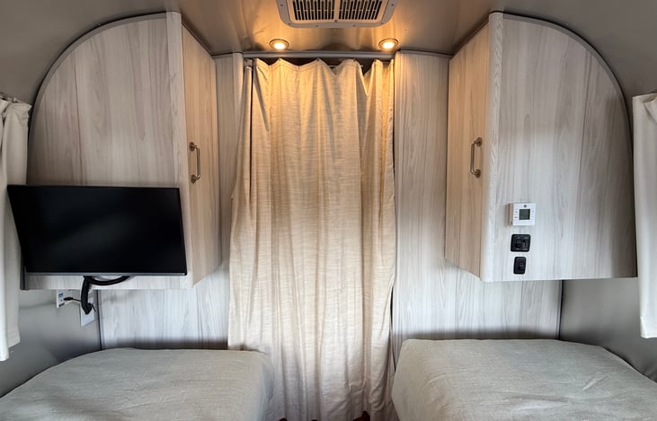 The bedroom also has a TV and is separated from the rest of the trailer with a privacy curtain. A thermostat controls the AC for this zone.
