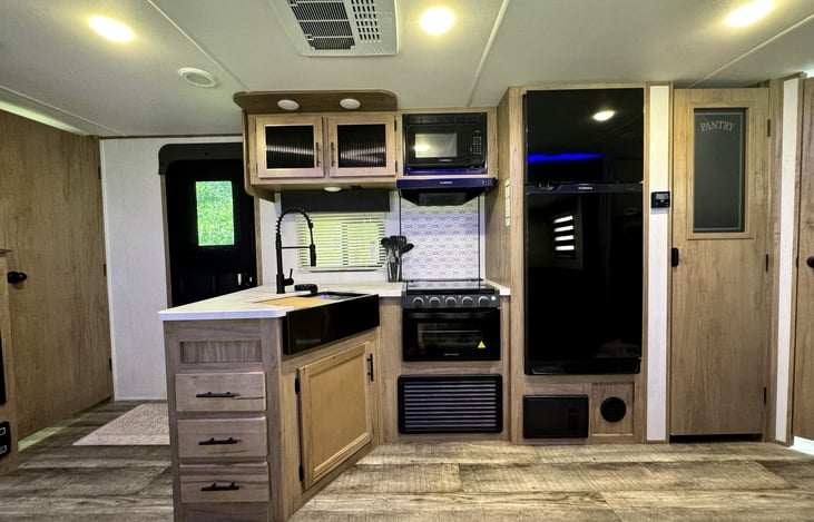 Fully equipped kitchen with residential refrigerator, oven, microwave, and farmhouse sink.