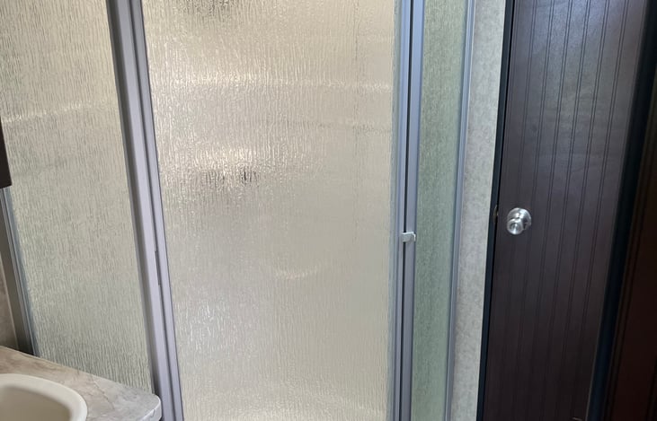Corner shower with glass doors.