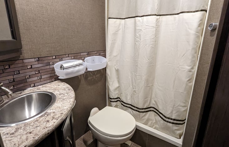 spacious bathroom with porcelain throne, above and below sink storage, special rv tp, shampoo, conditioner and body wash provided