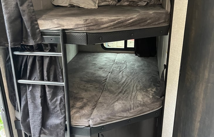 The RV includes double bunks, with storage space underneath the bottom bunk—ideal for luggage, gear, or toys. The master bed includes under-bed storage, and the thoughtful layout offers privacy and co
