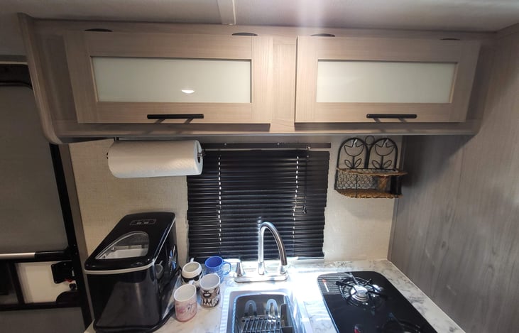 Cabinets above kitchen have dishes and supplies