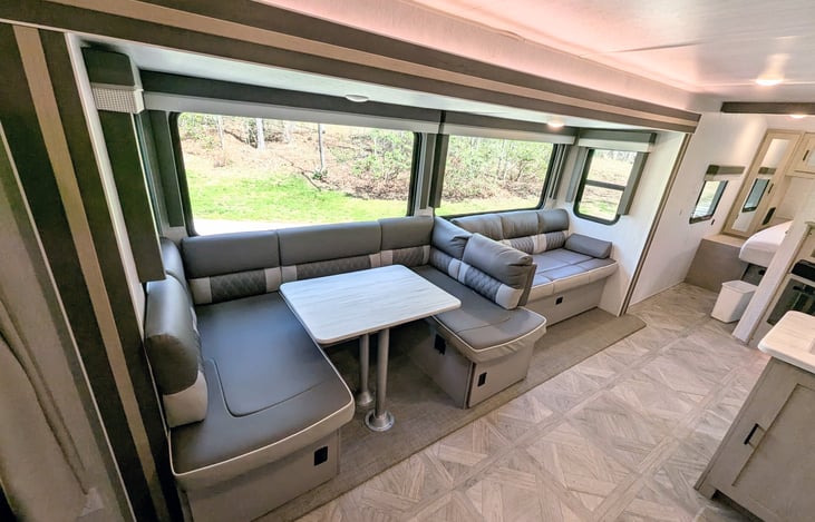 Bright and modern interior with a Custom King bed, double bunks, and a Versa-Lounge slide. Features a 30” fireplace, panoramic windows, 10.7 cu ft fridge, and a walk-in closet. Luxury camping at its f