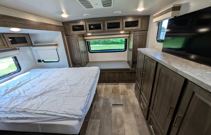 Private front bedroom features a walk-around Queen bed, TV, ample wardrobe storage, and a cozy built-in window seat nook—perfect for relaxing with a book! Full of natural light from 6 windows.