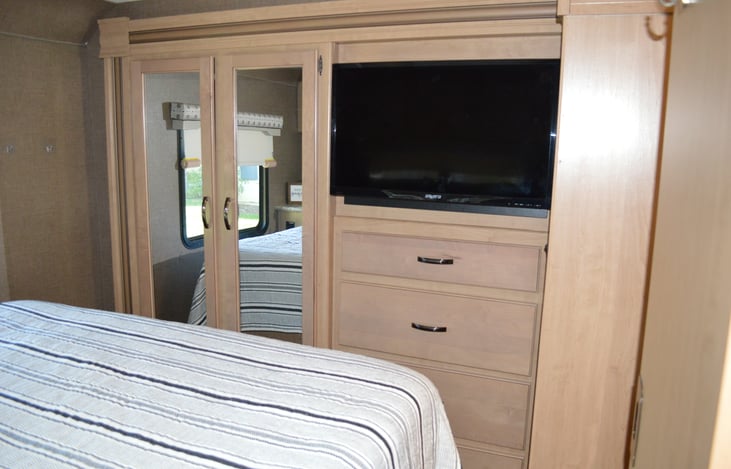 Master bedroom TV, dresser drawers and space to hang clothes.