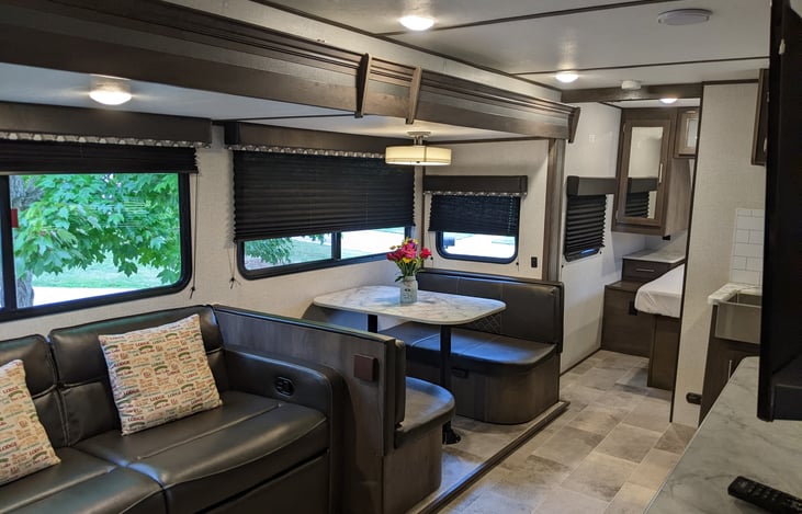 The lounge area with plenty of windows, a sofa with a footrest, dinette area. The bedroom is also visible.