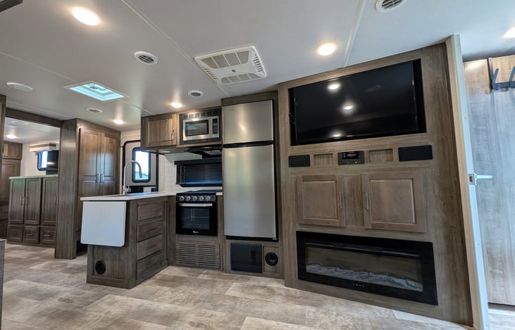 Spacious open-concept living area w/ dual recliners, TV & fireplace. Full kitchen features a residential fridge, 3-burner stove, oven, microwave, deep sink & booth dinette! Natural light throughout.