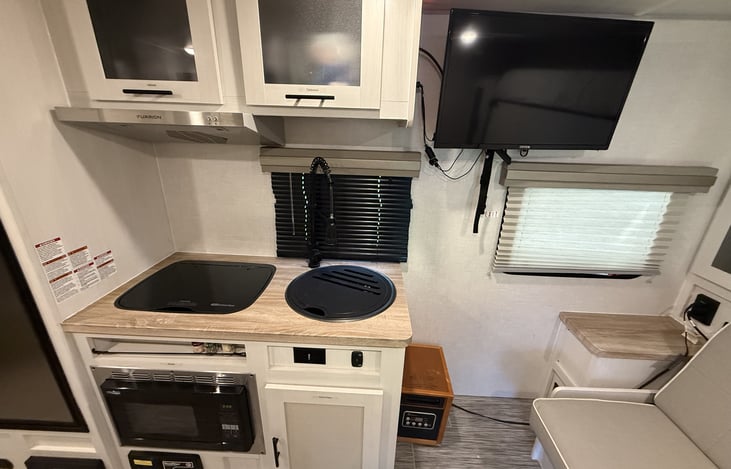 Kitchenette with stove top, sink, and convection microwave oven. Pots, Pans, cooking and eating utensils, plates, bowls, and cup storage. Even has a floor sweep vacuum.