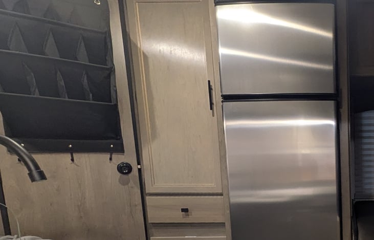 The fridge runs off the 12V system making the (7.5 gallons) of propane for the 3-burner stove, hot water and furnace last longer.