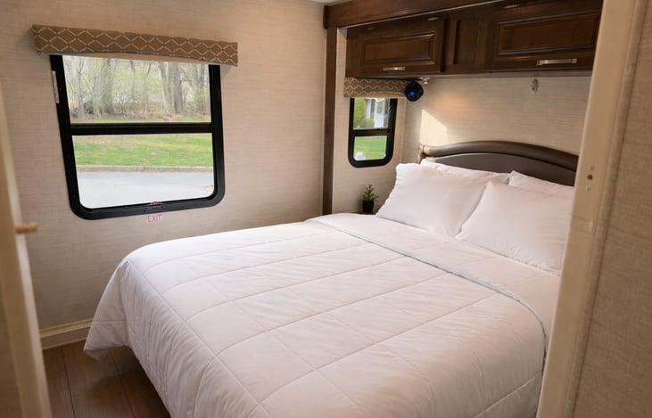 Master bedroom with queen-size bed, tv with Roku, closet/ drawers and large mirrors.