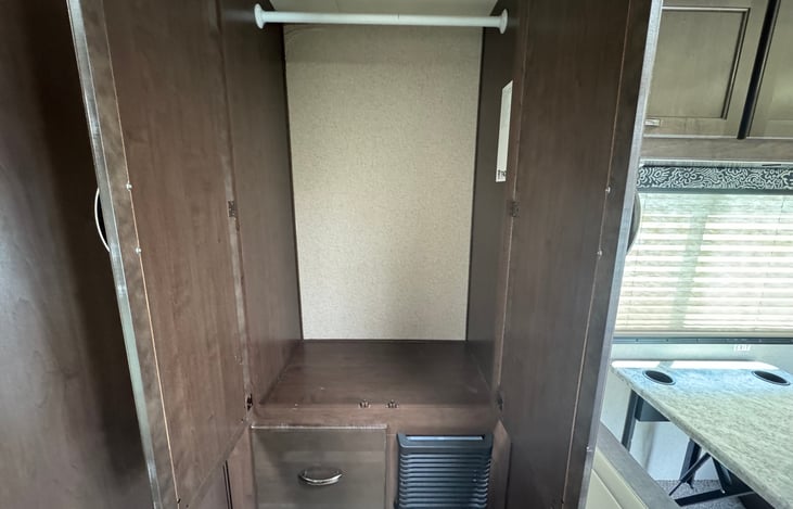 Hanging clothes closet.  Linen drawer and furnace vent seen below.