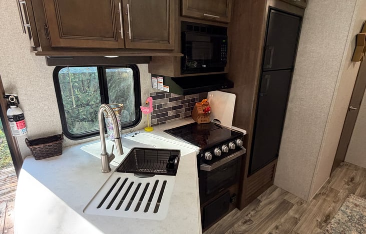 Kitchen with gas stove top, microwave, oven, fridge and freezer, and double sink