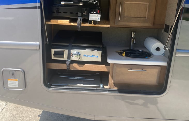 Outdoor kitchen with propane grill and flattop. Grilling accessories and sink