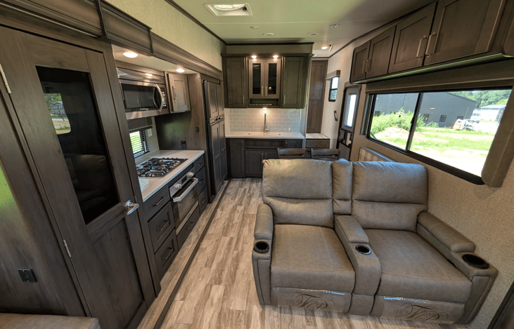 Gourmet galley & rear den retreat! Includes a 12 cu ft fridge, pantry, stove/oven, dual sofas, theater seats, 50" TV, electric fireplace, and 3 slides for spacious high-end living.
