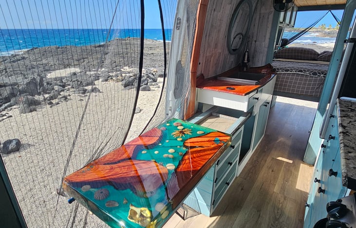 The river pour table is on drawer slides and pulls out to meet the passenger seat that swivels to face the rear.  The table slides to the back over the cabinet when not in use.